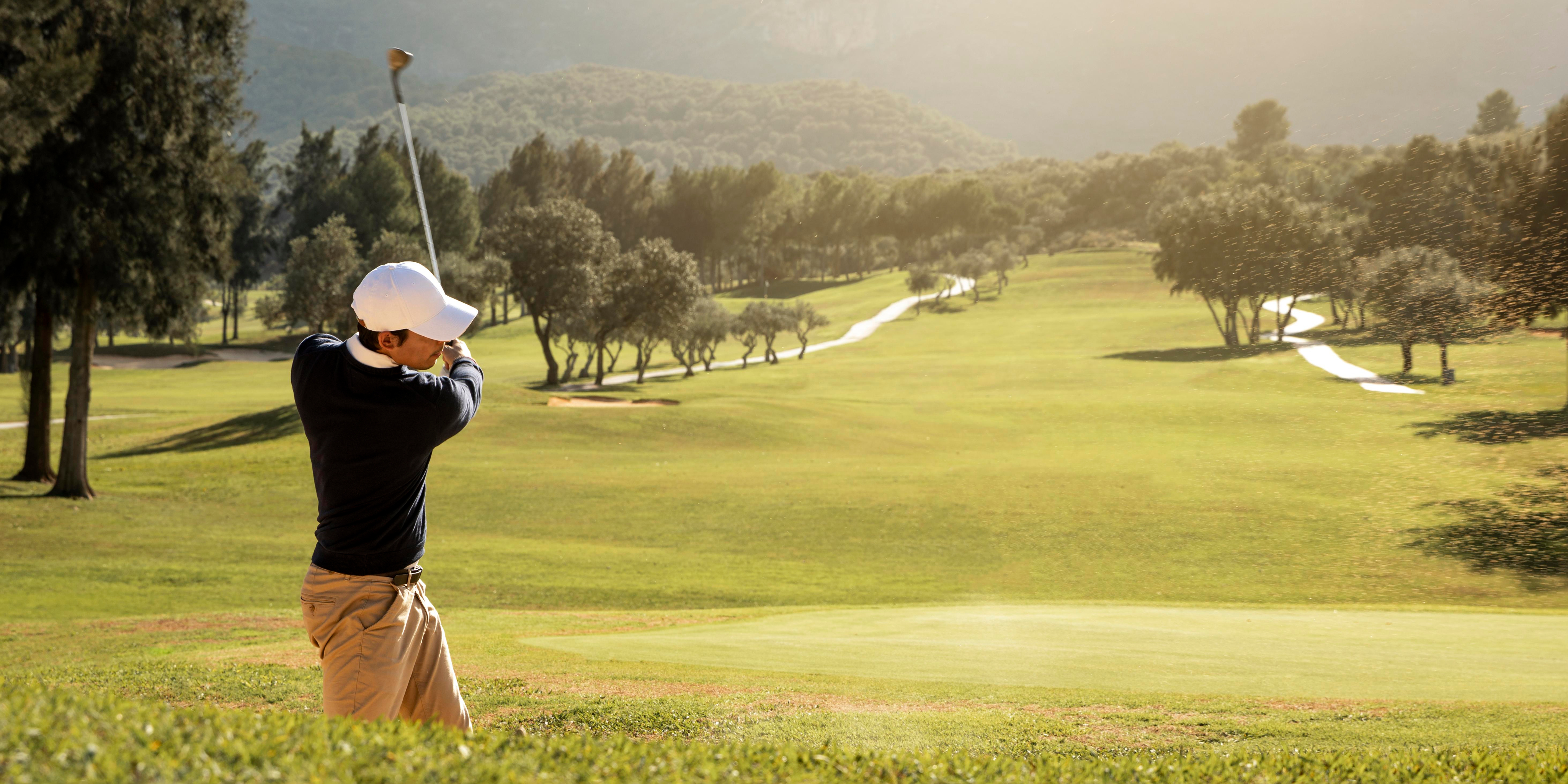 A man playing golf on a lush green course.