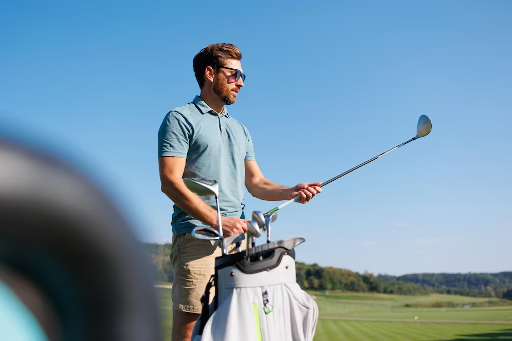 Man in a blue polo shirt preparing to take a swing on the golf course.